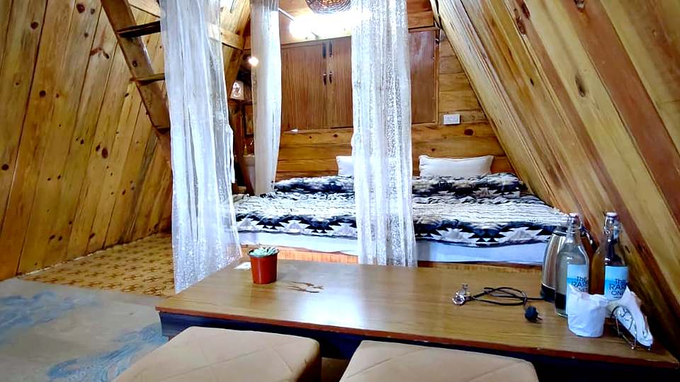 Sitting area inside an A-frame cottage at The Rare One’s Resort, Mukteshwar