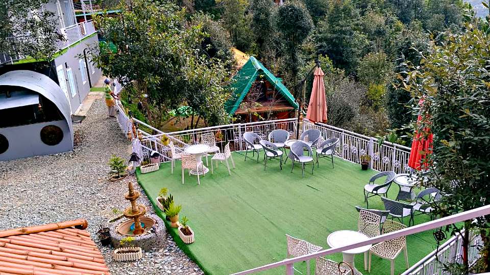 Lawn seating surrounded by forest at The Rare One’s Resort, Mukteshwar