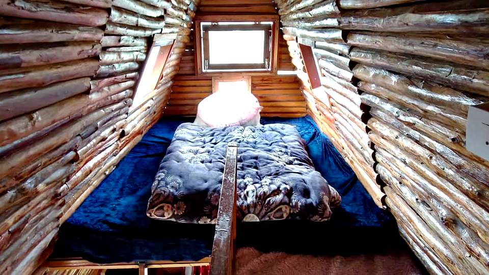 Loft bed under the log A-frame roof at The Rare One’s Resort, Mukteshwar