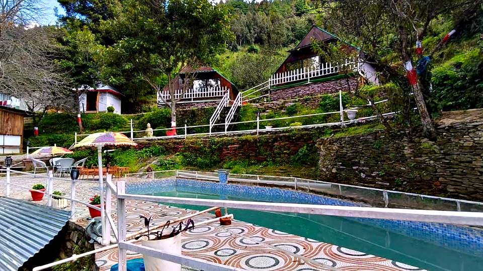 Pool deck with umbrellas at The Rare One’s Resort, Mukteshwar