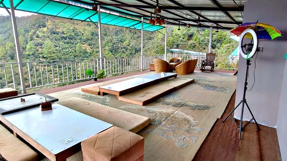 Covered terrace with low tables overlooking the forest at The Rare One’s Resort, Mukteshwar